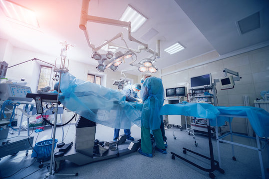 Process Of Trauma Surgery Operation. Group Of Surgeons In Operating Room With Surgery Equipment.