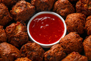 Indian Pakora snack spicy onion, red pepper with chilli sauce in a black plate