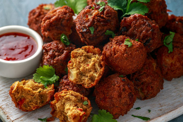 Indian Pakora snack spicy onion, red pepper with chilli sauce on white wooden board