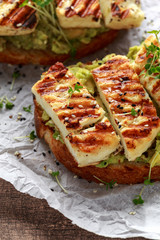 Avocado and grilled haloumi cheese toast with nigella and sesame seeds on crumpled paper. healthy breakfast