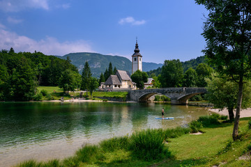 Fototapeta na wymiar Church of St John the Baptist with bridge. Lake Bohinj. Triglav National Park, Julian Alps, Slovenia