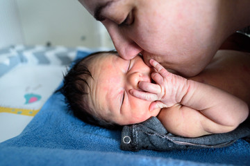 Mamá besando a bebé tumbado