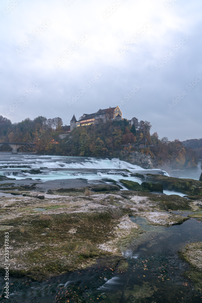 Poster vertical landscape view of the famous rhine falls in switzerland in the evening during twilight