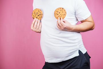weight gain, hormonal imbalance, eating junk food. obese man with chocolate cookies.
