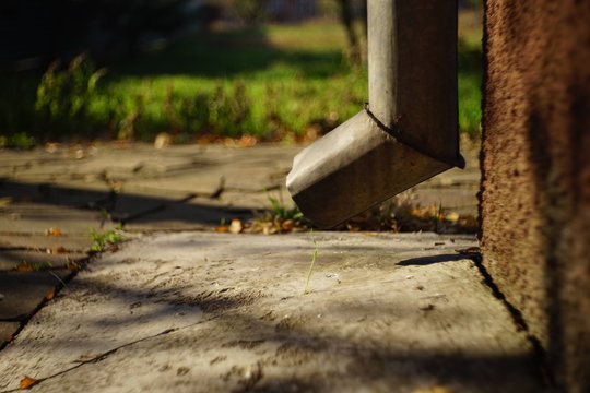 bottom of the drain pipe at the corner of the house, autumn day