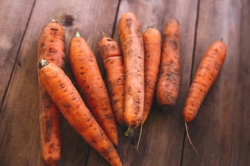 Fresh carrots lie on a table made of natural wood of dark color. Healthy Eating