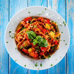 Pasta with meat, tomato sauce and vegetables on wooden table
