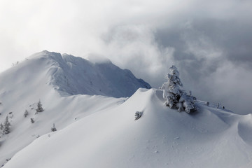 Mountain landscape. Fog and clouds on top. Snow-covered slopes.