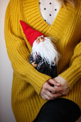 Young woman holding small santa claus. Christmas toy in the hands of the girl. Celebration season and christmas concept