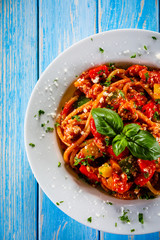Pasta with meat, tomato sauce and vegetables on wooden table