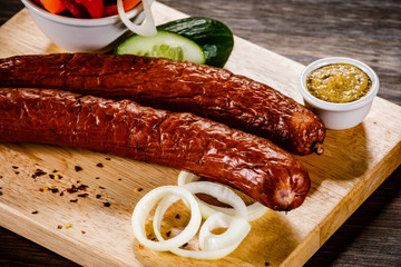 Raw sausages with vegetables on cutting board