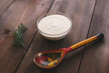 Fresh sour cream in a bowl with a wooden spoon. Russian kitchen