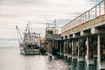 Fototapeta premium Old little ship or boat at concrete sea port pier