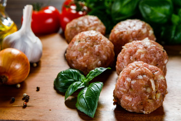 Raw meatballs on cutting board on wooden background