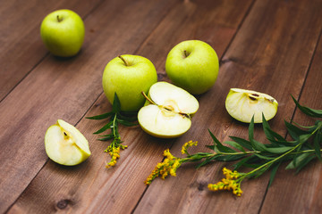 Large juicy green apples and their pieces on a dark wooden table