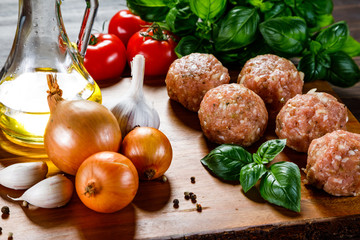 Raw meatballs on cutting board on wooden background