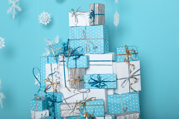 Christmas copyspace interior and decorations. Snowflakes and gift boxes with bow in front of by wall turquoise wall in holiday winter modern room. Postcard Xmas background.