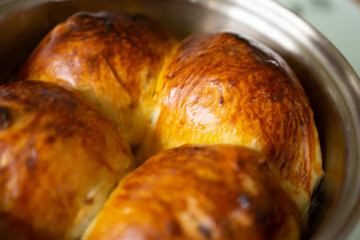 Homemade raisin danish style bread in a stainless steel pan on a glass table