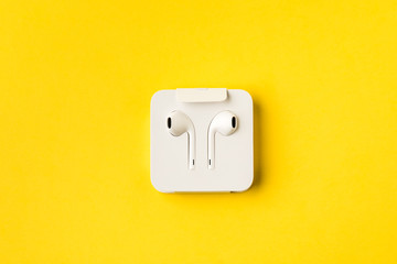 Headphones in paper storage case, on yellow background.