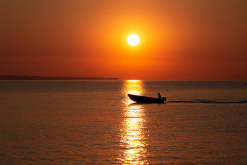 Sunrise landscape  with fishermans boat in sun way on surface of  the sea.