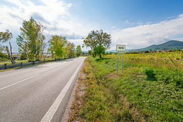 Town sign and road leading through fields into Trstin - a village in Slovakia