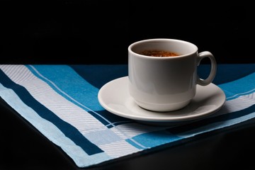 White cup of coffee on fabric background