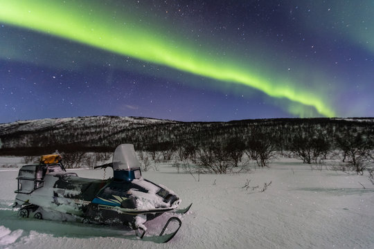 Beautiful green northern lights and snowmobile on foreground