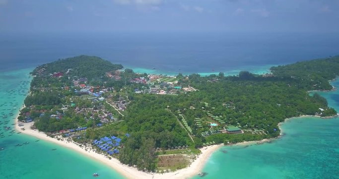 High elevation overview of tourist holiday tropical island and surrounding colorful sea seen in RL pan aerial drone view on sunny day above Ko Lipe, Thailand. 4k 1.9:1 23.976fps