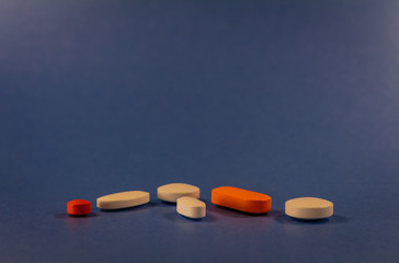 Pills of various colors on a neutral blue background.