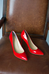 red patent leather shoes,  red leather shoes on brown chair (top view)