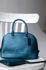 women leather bag and purse(dark green, blue, turquoise color) on a white wooden chair in studio, advertising shooting bags, presentation bags, leather handbag