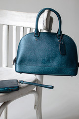 women leather bag and purse(dark green, blue, turquoise color) on a white wooden chair, advertising shooting bags, presentation bags, leather handbag.
