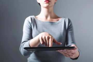 Young woman using her tablet on a gray background