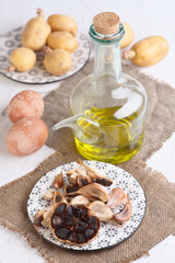 Black garlics eggs potatoes and other raw ingredients on textured white base