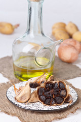 Black garlics eggs potatoes and other raw ingredients on textured white base