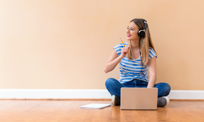 Young woman studying on her laptop computer against a big interior wall - Powered by Adobe