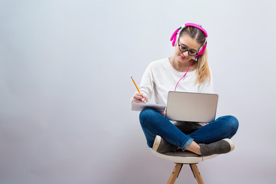 Young Woman Studying On Her Laptop Computer On A Gray Background