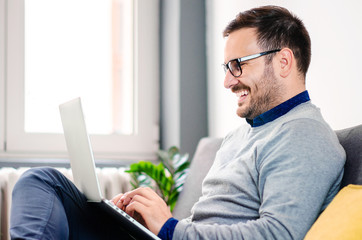 Handsome young man with glasses using laptop at home