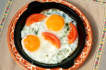Fried eggs with tomatoes in a pan
