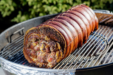 Roasted rolled pork cooking on the barbecue grill