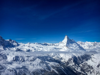 Majestic Matterhorn mountain in front of a blue sky with clouds.