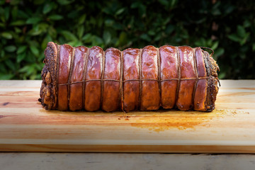 Whole Cooked roasted rolled pork on chopping board