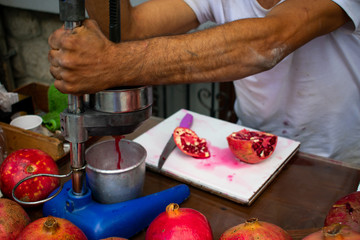 man squeezing fresh pomegranate juice in traditional way close up in Antalya, Turkey