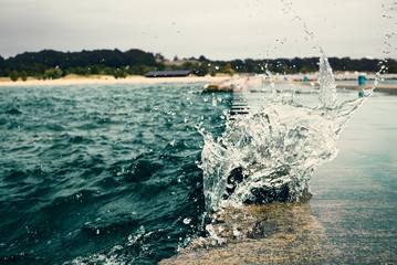 Wave breaking on breakwater with green metall bollards in Michigan