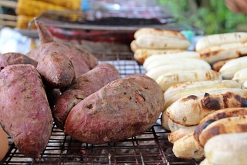 Grilling potato and banana / Purple potatos and bananas are grilling on stove. Famous Asian street food especially in cool day.