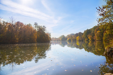 Beautiful autumn colorful foliage with lake reflection and blue sky.