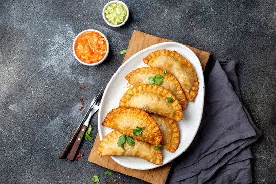 Latin American fried empanadas with tomato and avocado sauces. Top view