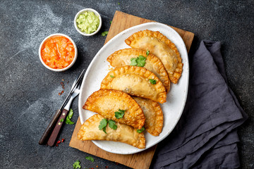Latin American fried empanadas with tomato and avocado sauces. Top view