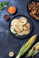 COLOMBIAN FOOD. Maize AREPAS and fried pork chicharron ans colombian tomato sauce. Top view. Black background