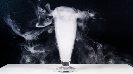 high glas filled with smoke on a white table with a black background, smoke in glas, 